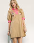 Woman wearing a beige dress with pink accents and embroidery on a plain background