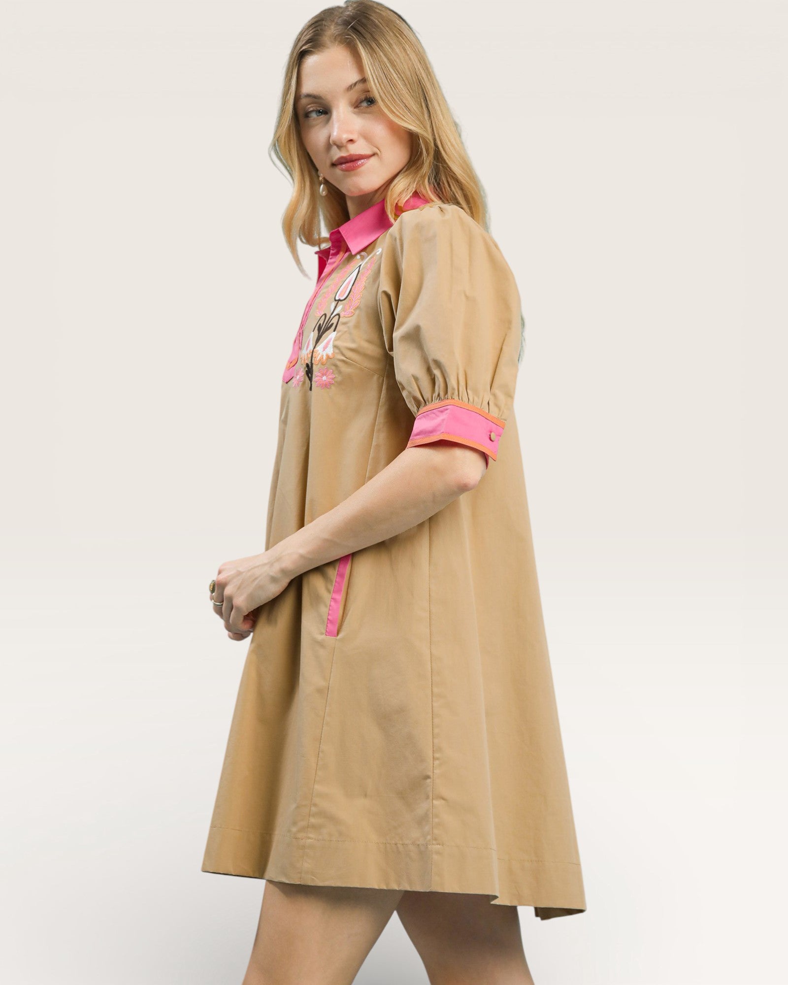 Woman wearing a beige dress with pink accents on a white background