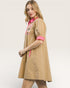Woman wearing a beige dress with pink accents on a white background