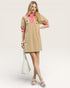 Woman wearing a beige dress with pink accents on a white background