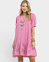 Woman wearing a pink dress with floral embroidery on a white background