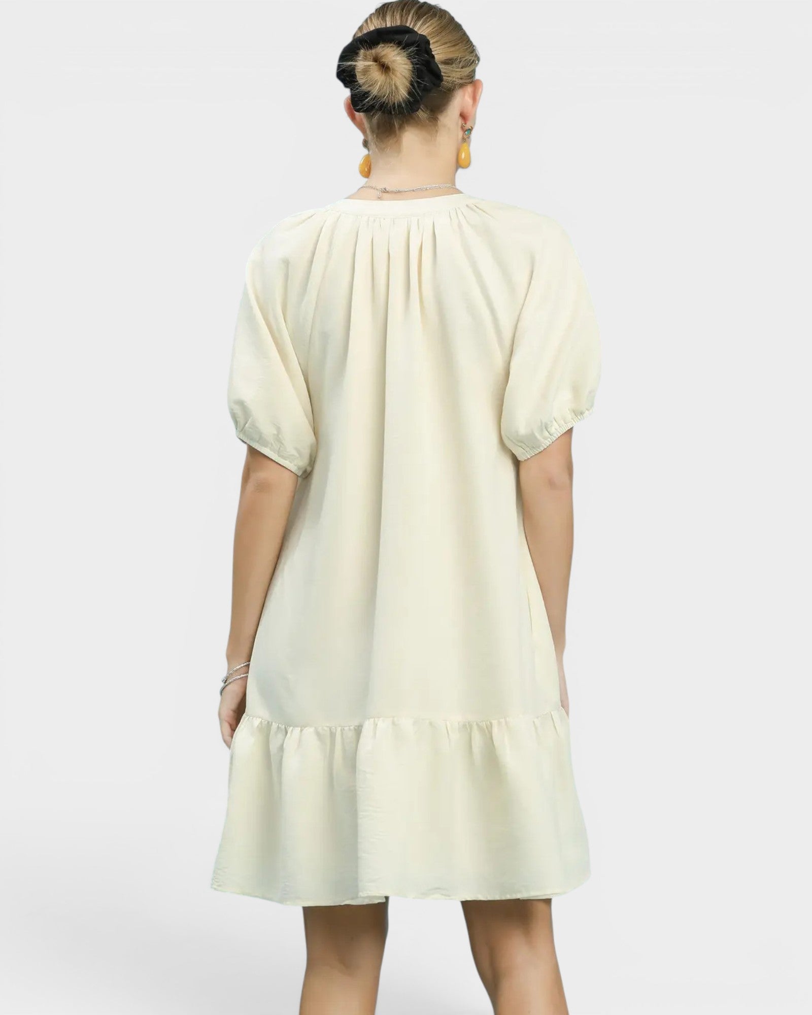 Person wearing a light-colored dress with a plain background