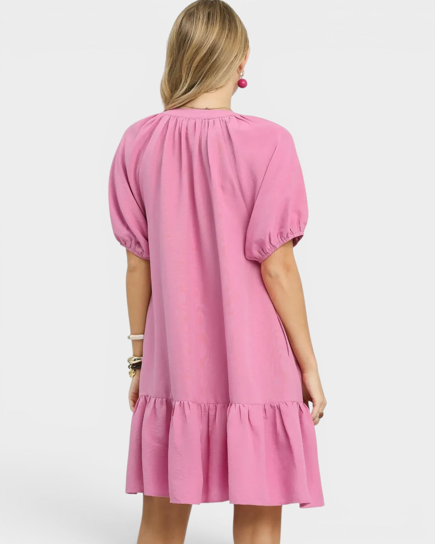 Pink dress with puff sleeves worn by a person on a white background