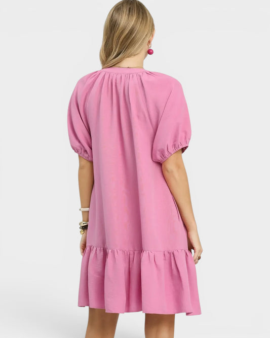 Pink dress with puff sleeves worn by a person on a white background