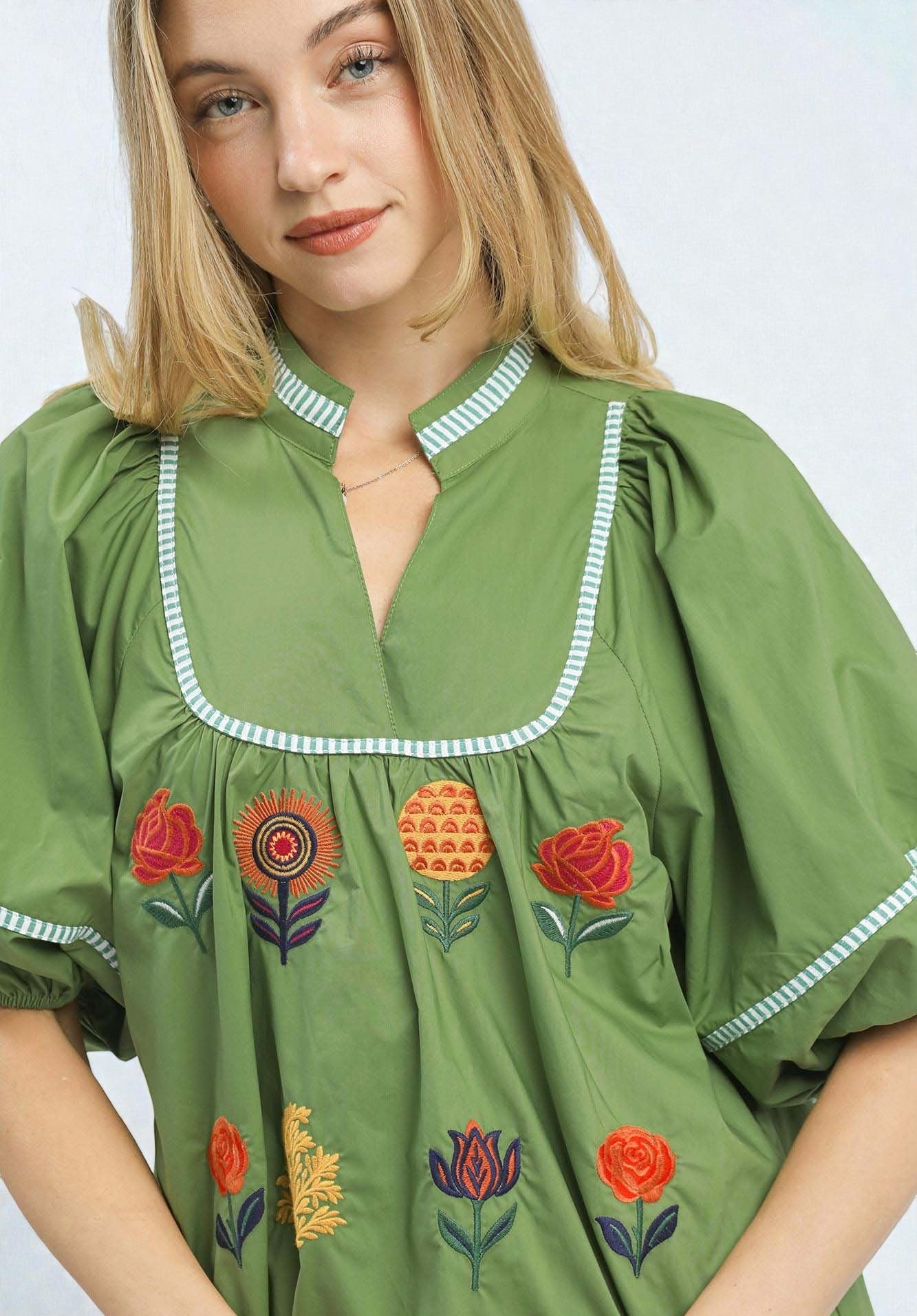 Woman wearing a green dress with floral embroidery on a white background