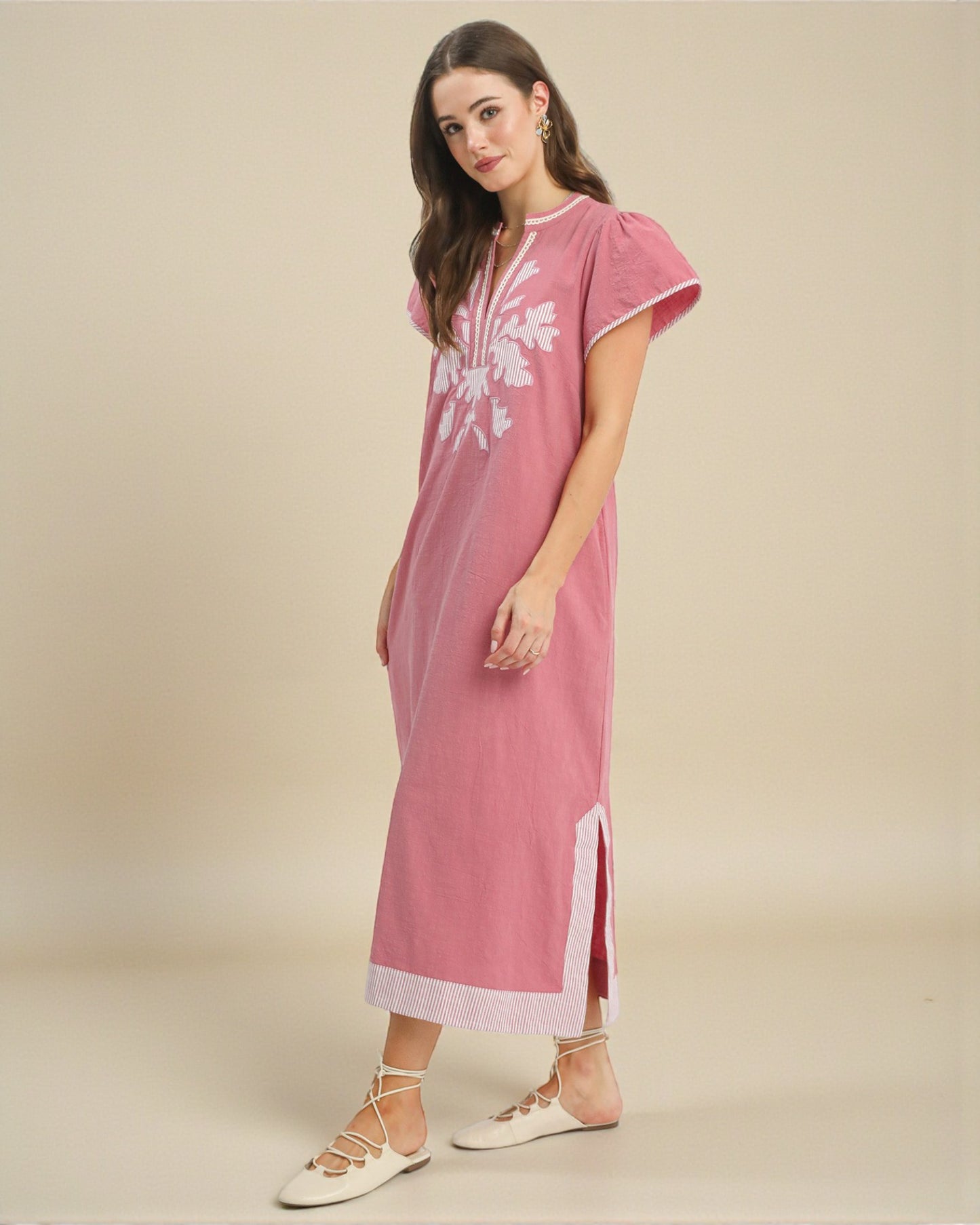 Woman wearing a pink dress with white floral patterns on a beige background