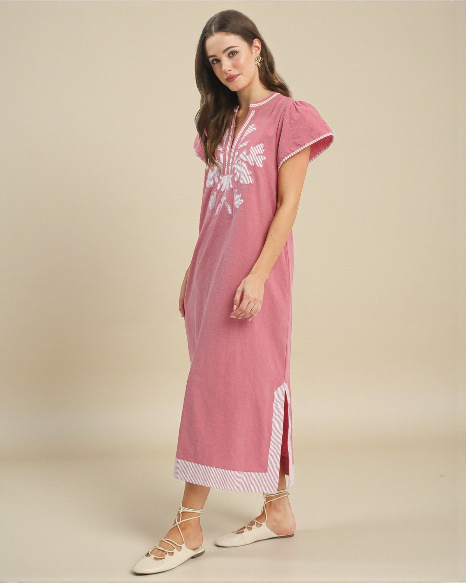 Woman wearing a pink dress with white floral patterns on a beige background