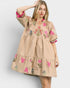 Woman wearing a beige dress with floral embroidery on a white background