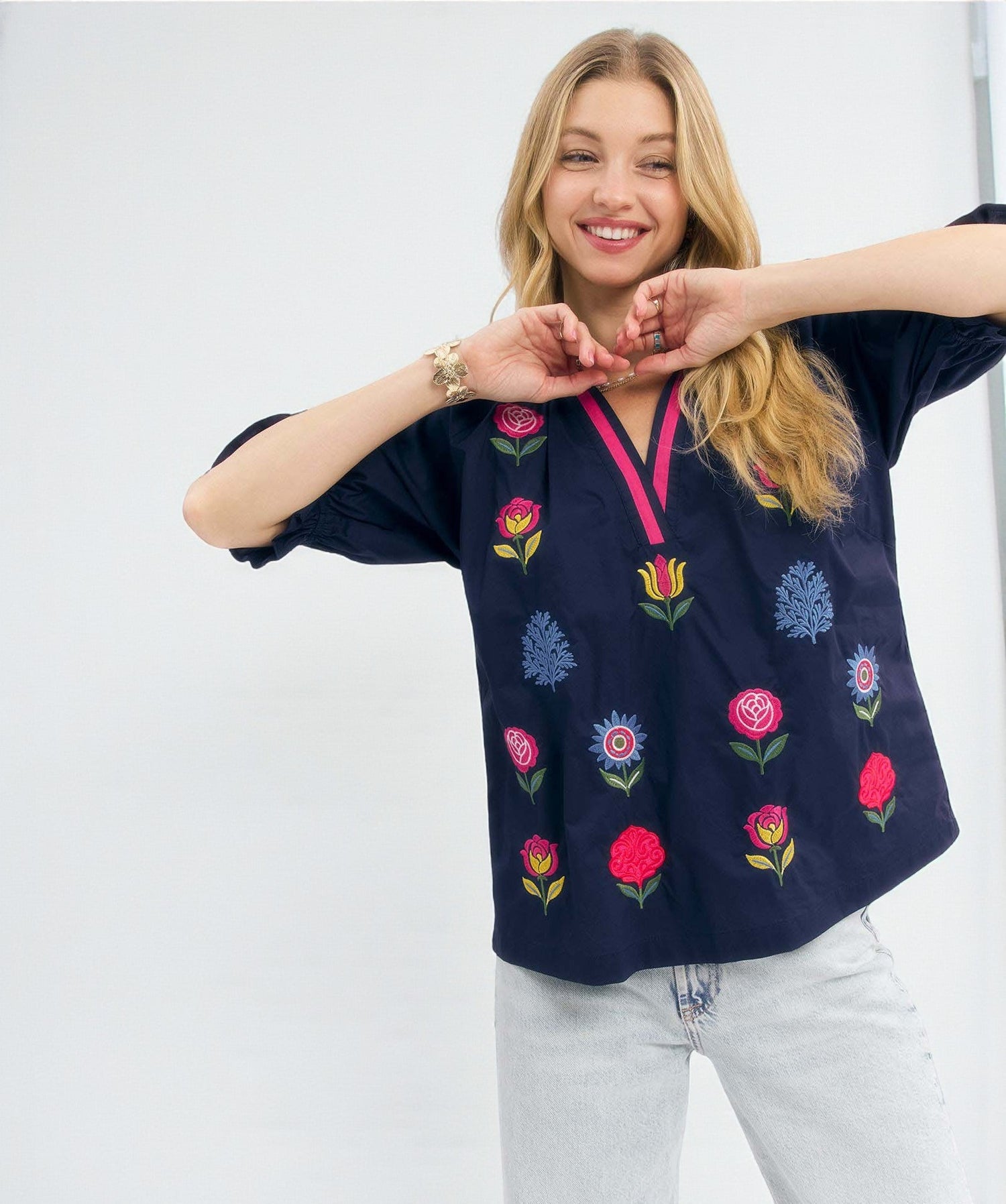 Woman wearing a navy blue blouse with colorful floral embroidery on a white background