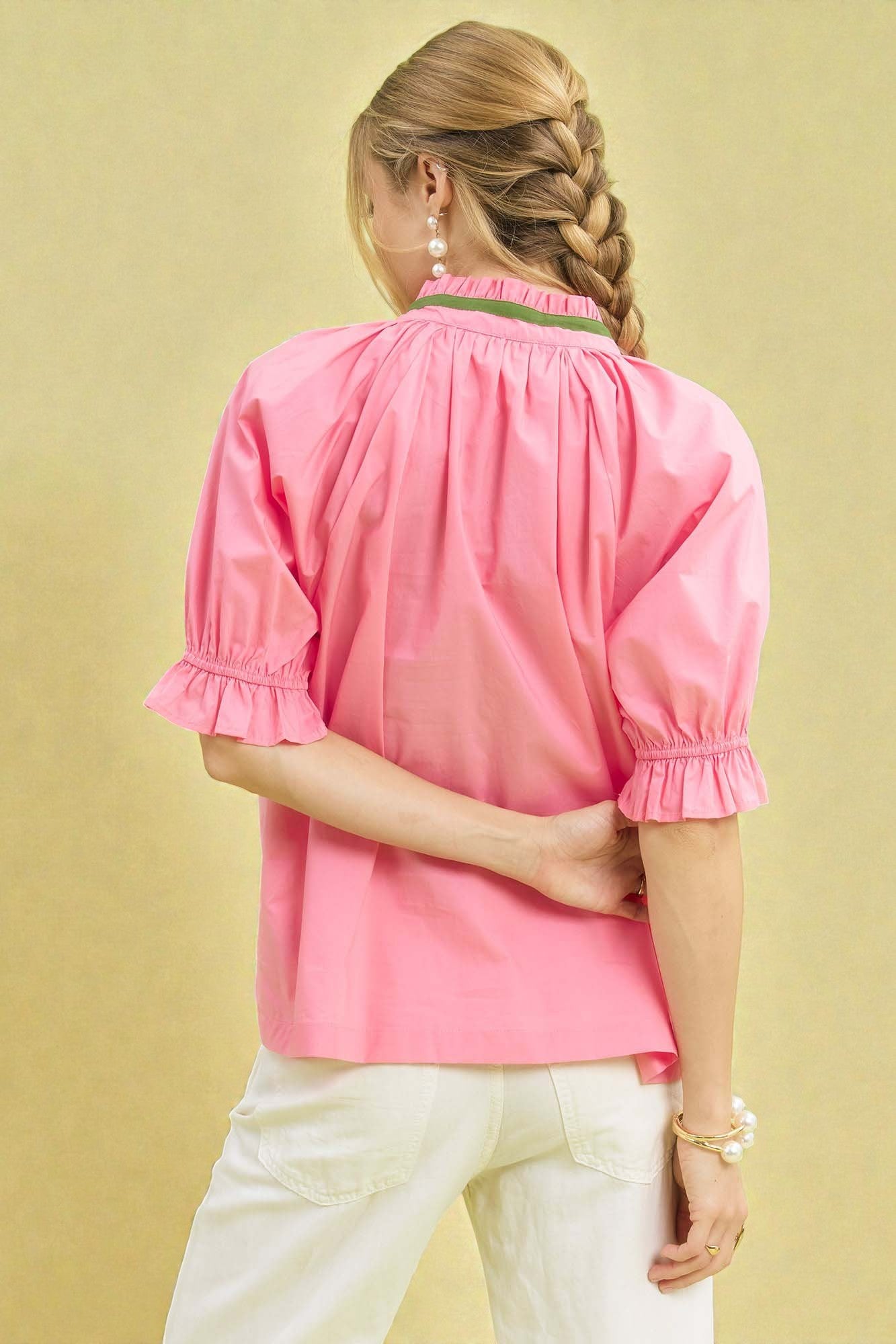 Person wearing a pink blouse with puff sleeves on a beige background