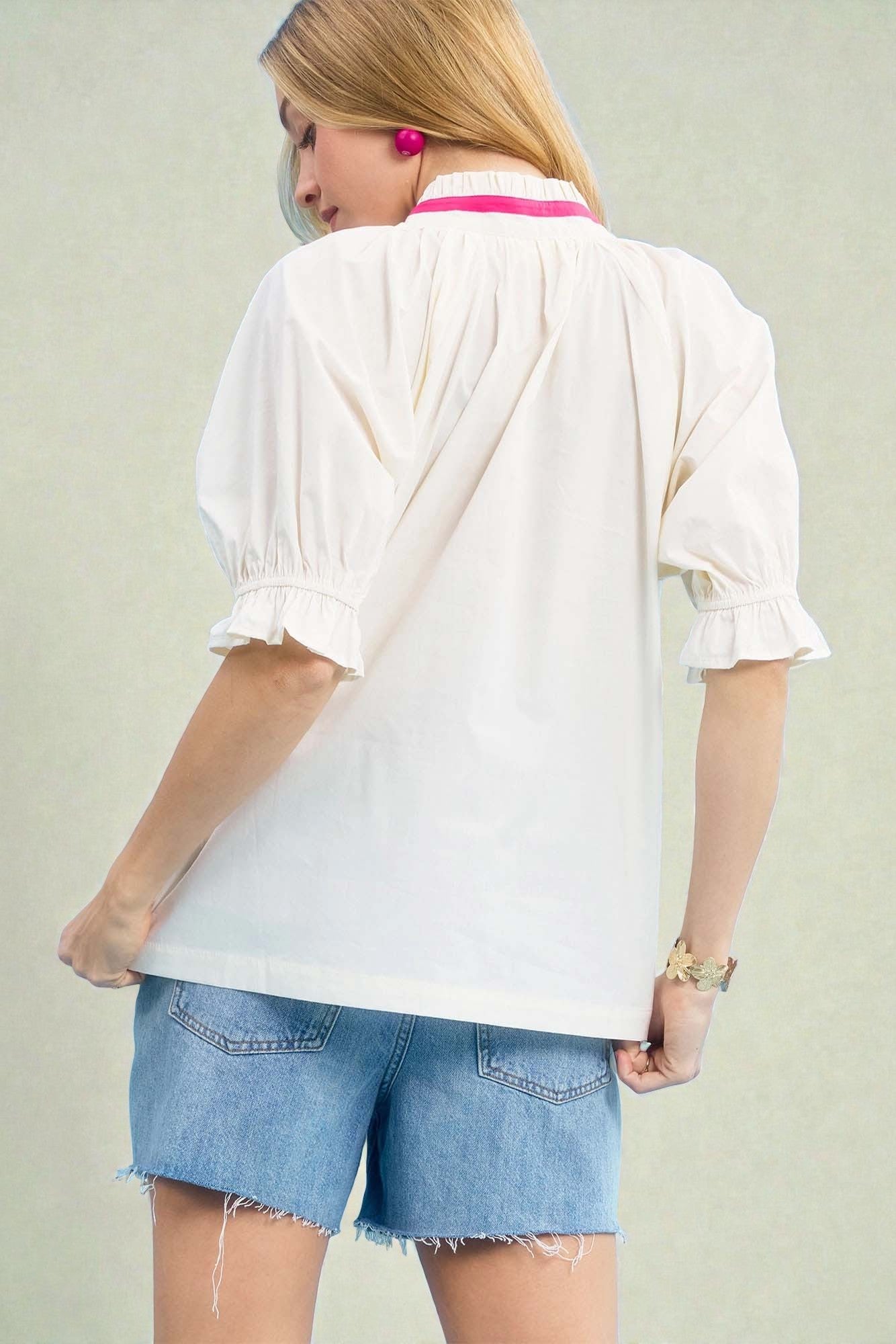 Person wearing a white blouse and denim shorts on a plain background