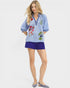 Woman wearing a blue embroidered top and shorts on a white background