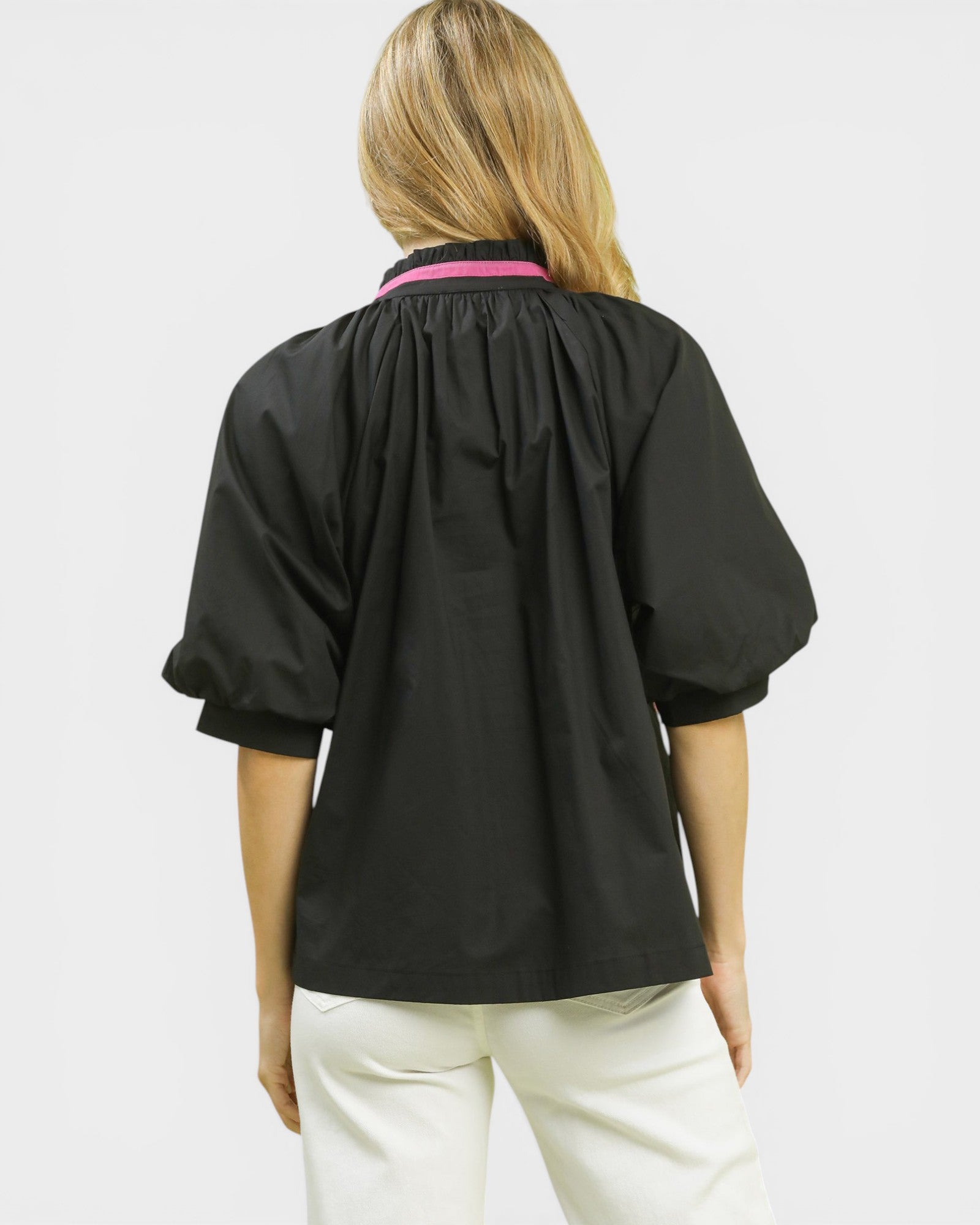 Person wearing a black shirt with a pink collar on a white background
