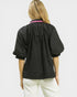 Person wearing a black shirt with a pink collar on a white background
