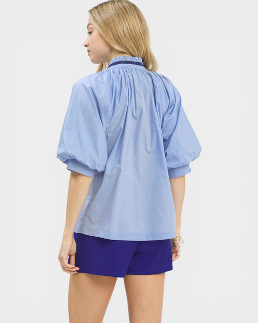 Woman wearing a light blue shirt and purple shorts on a white background