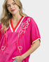 Woman wearing a pink embroidered dress with red accents on a white background