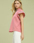 Woman wearing a pink top with embroidered details on a light green background