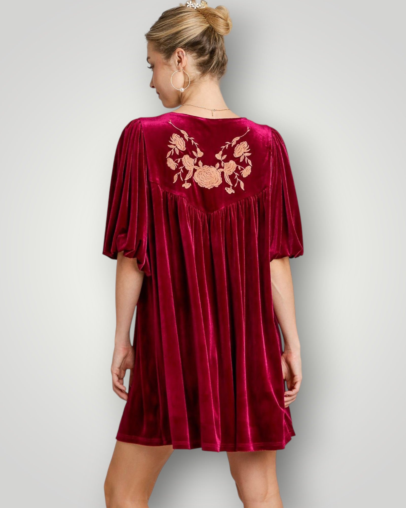 Red velvet dress with floral embroidery on the back, worn by a person against a plain background