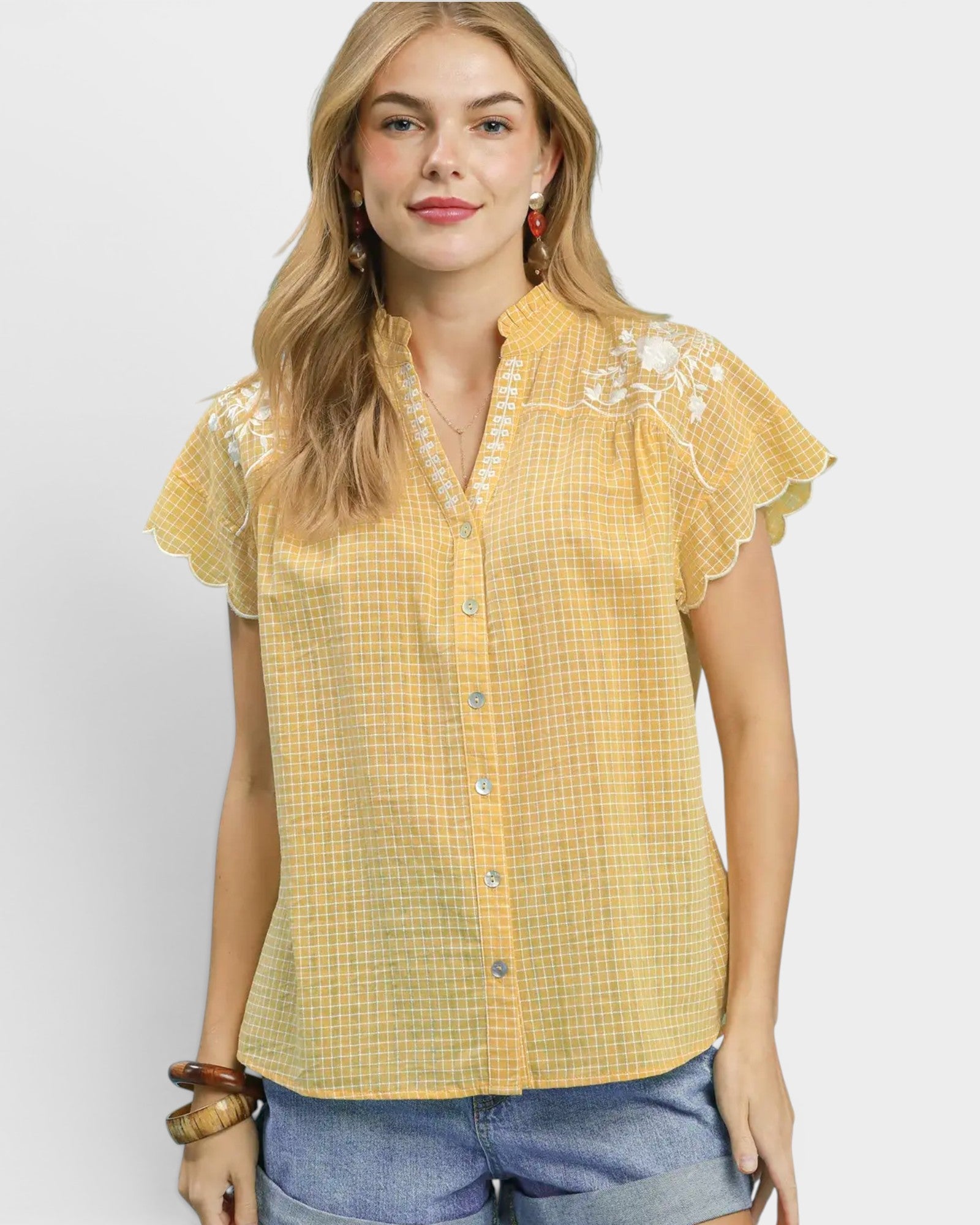 Woman wearing a yellow checkered blouse with lace details on a white background