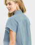 Woman wearing a blue checkered blouse with ruffled sleeves on a light gray background