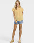 Woman wearing a yellow checkered blouse and denim shorts on a white background