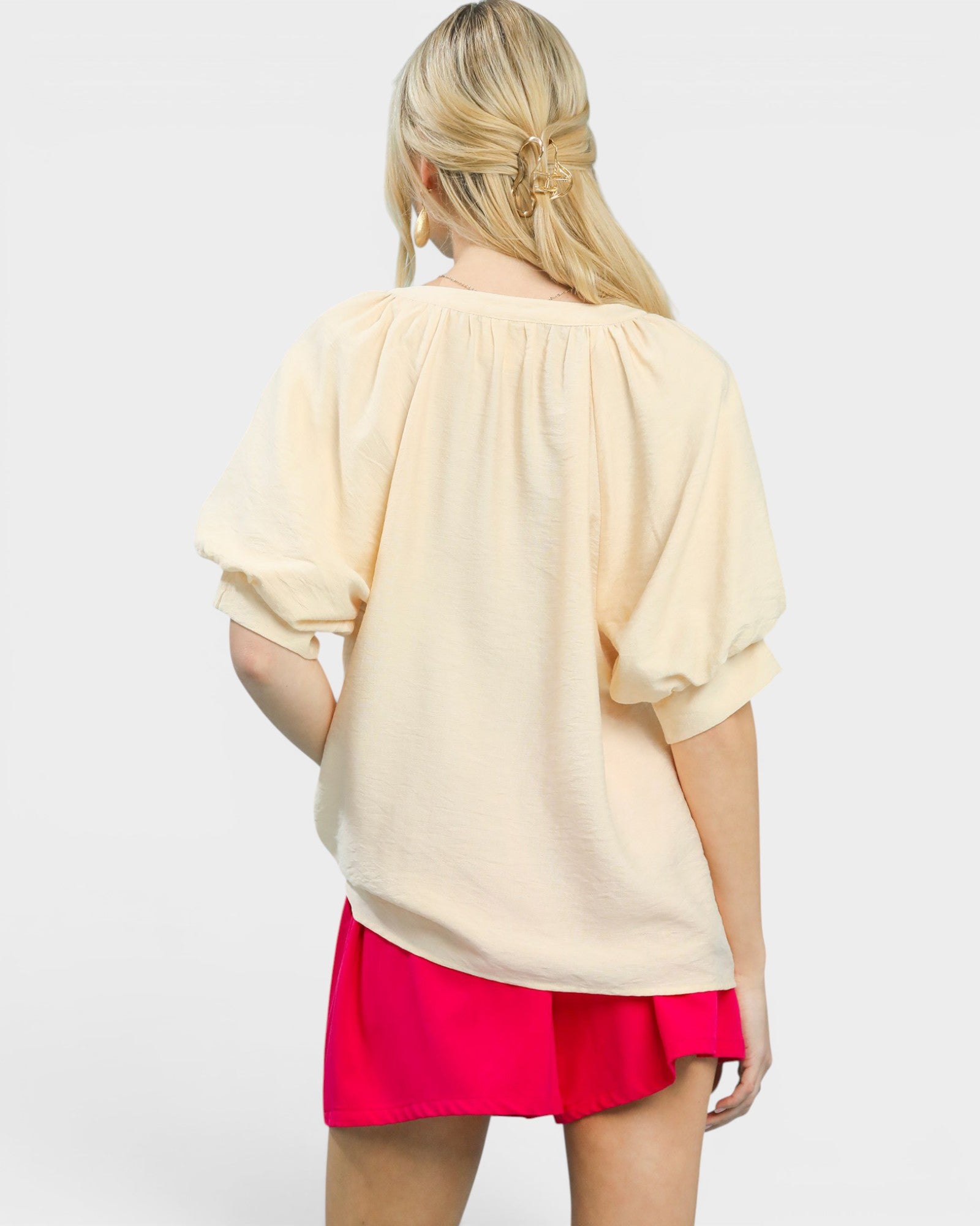 Woman wearing a beige top and pink skirt on a white background