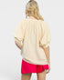 Woman wearing a beige top and pink skirt on a white background