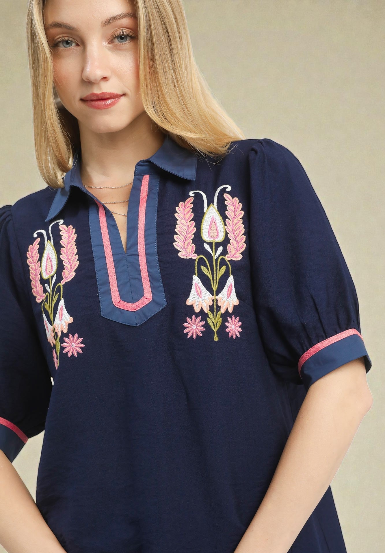 Navy blue blouse with floral embroidery on a neutral background