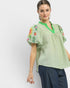 Woman wearing a green blouse with floral embroidery on a white background