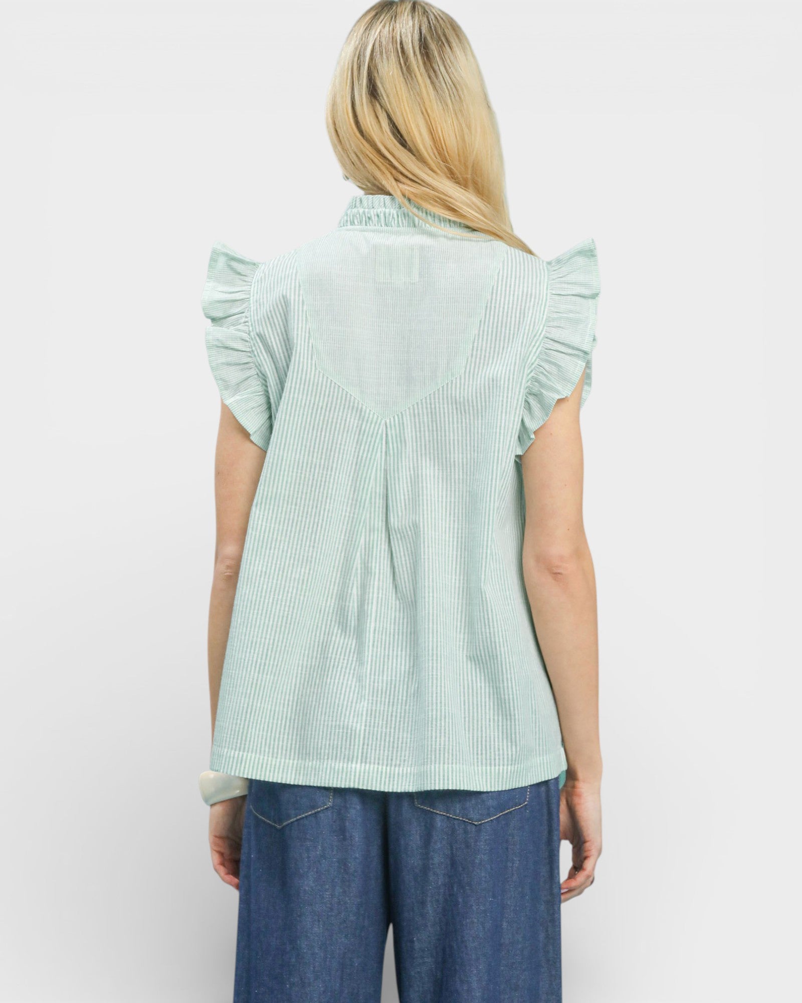 Light green ruffled sleeve blouse worn by a person on a white background