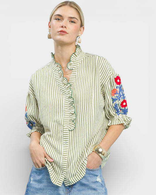 Woman wearing a green and white striped shirt with floral sleeves on a plain background