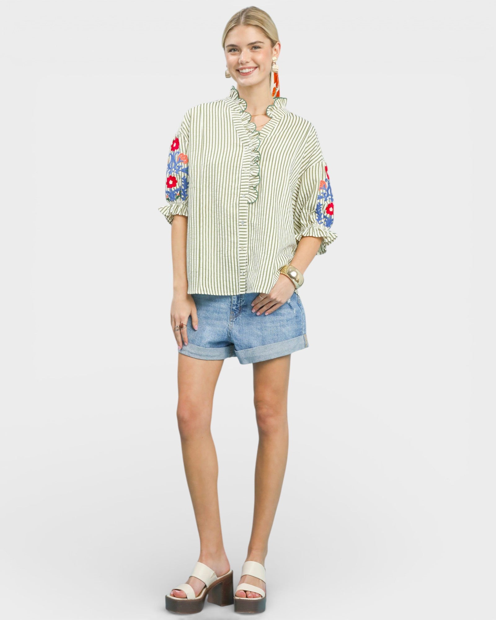 Woman wearing a striped shirt with floral sleeves and denim shorts on a white background