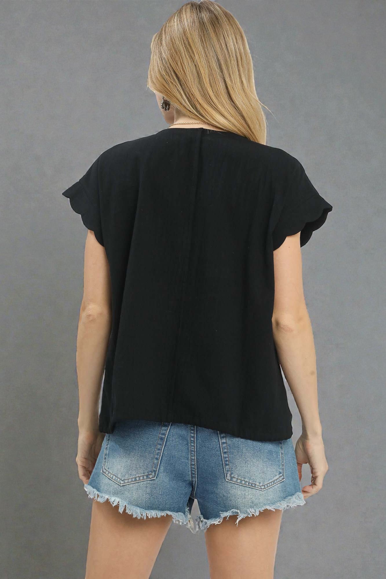 Person wearing a black top and denim shorts on a gray background