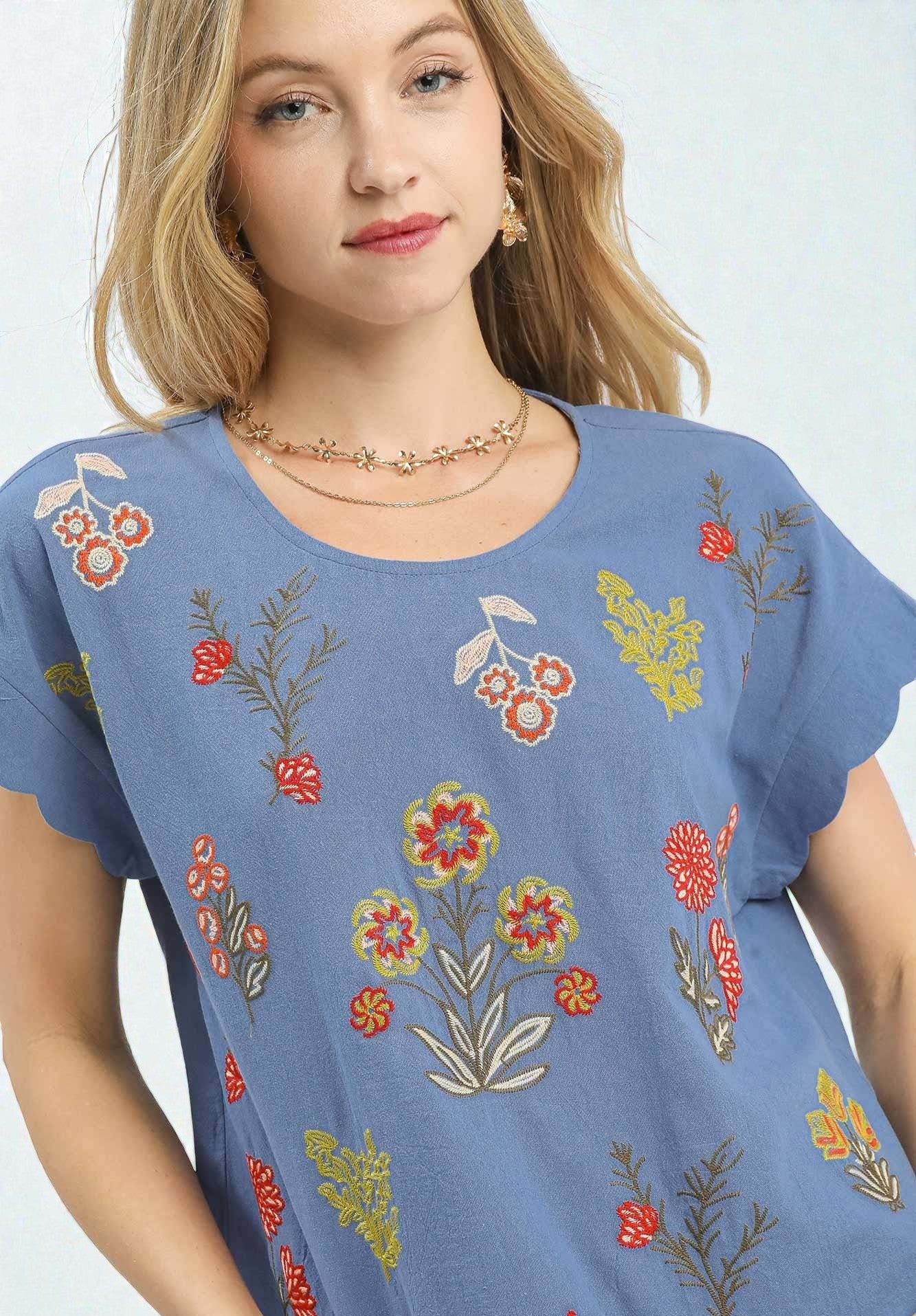 Woman wearing a blue t-shirt with floral patterns on a white background