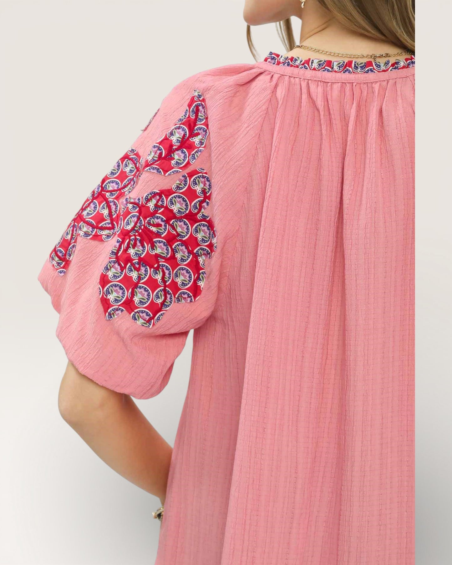 Pink dress with patterned sleeves on a white background