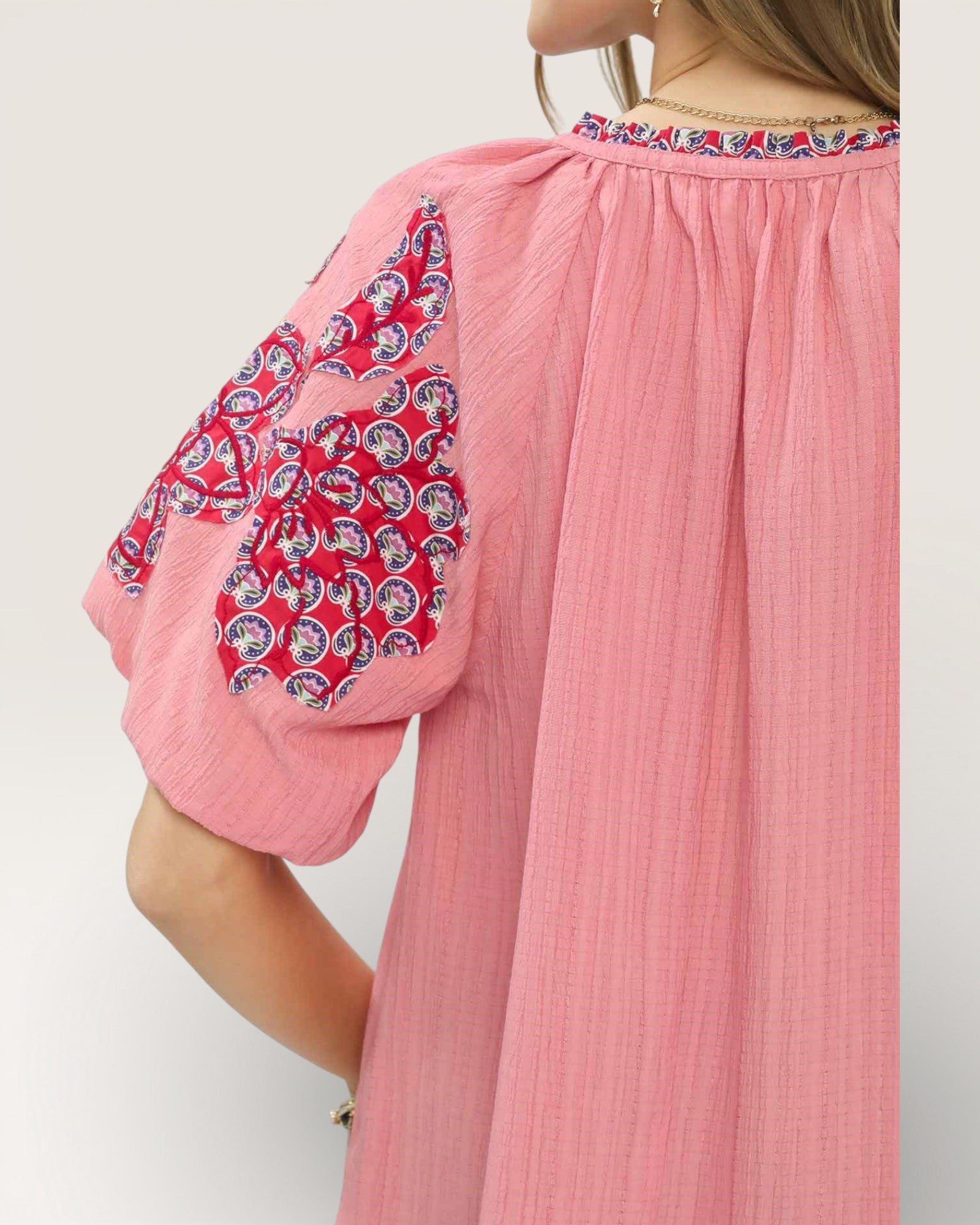 Pink dress with patterned sleeves on a white background