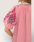 Pink dress with patterned sleeves on a white background