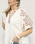 Woman wearing a white blouse with floral patterns on a plain background