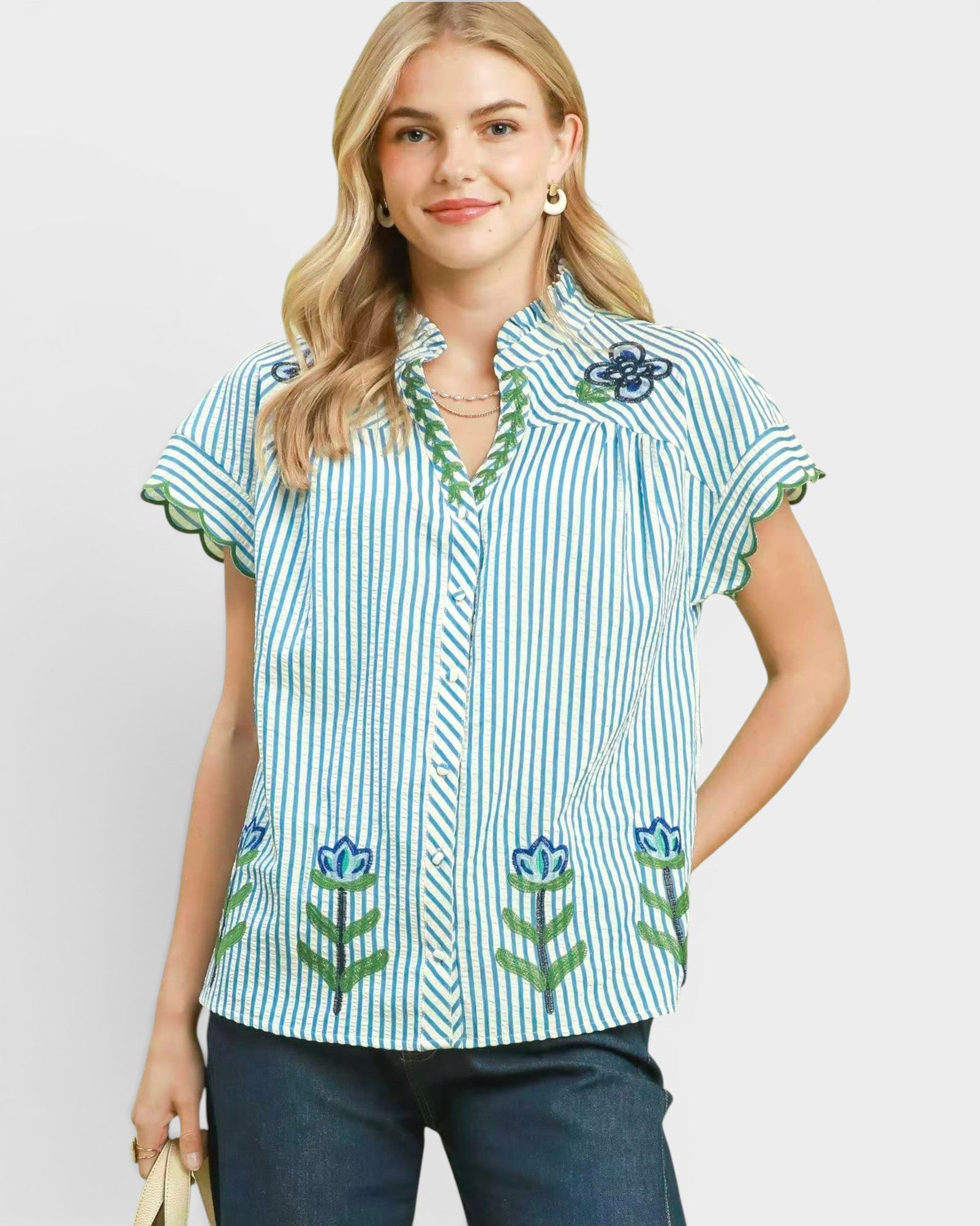 Woman wearing a blue and white striped shirt with floral patterns on a plain background