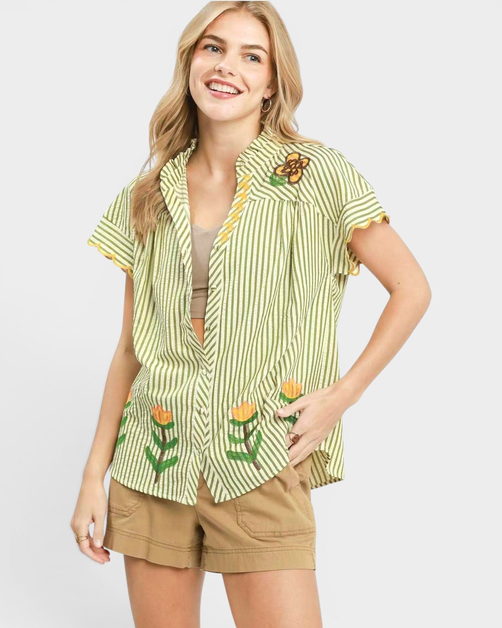 Woman wearing a green and white striped shirt with floral designs on a plain background