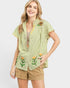 Woman wearing a green and white striped shirt with floral designs on a plain background
