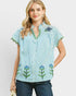 Woman wearing a blue and white striped shirt with floral patterns on a plain background