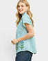 Woman wearing a blue and white striped shirt with floral details on a light gray background