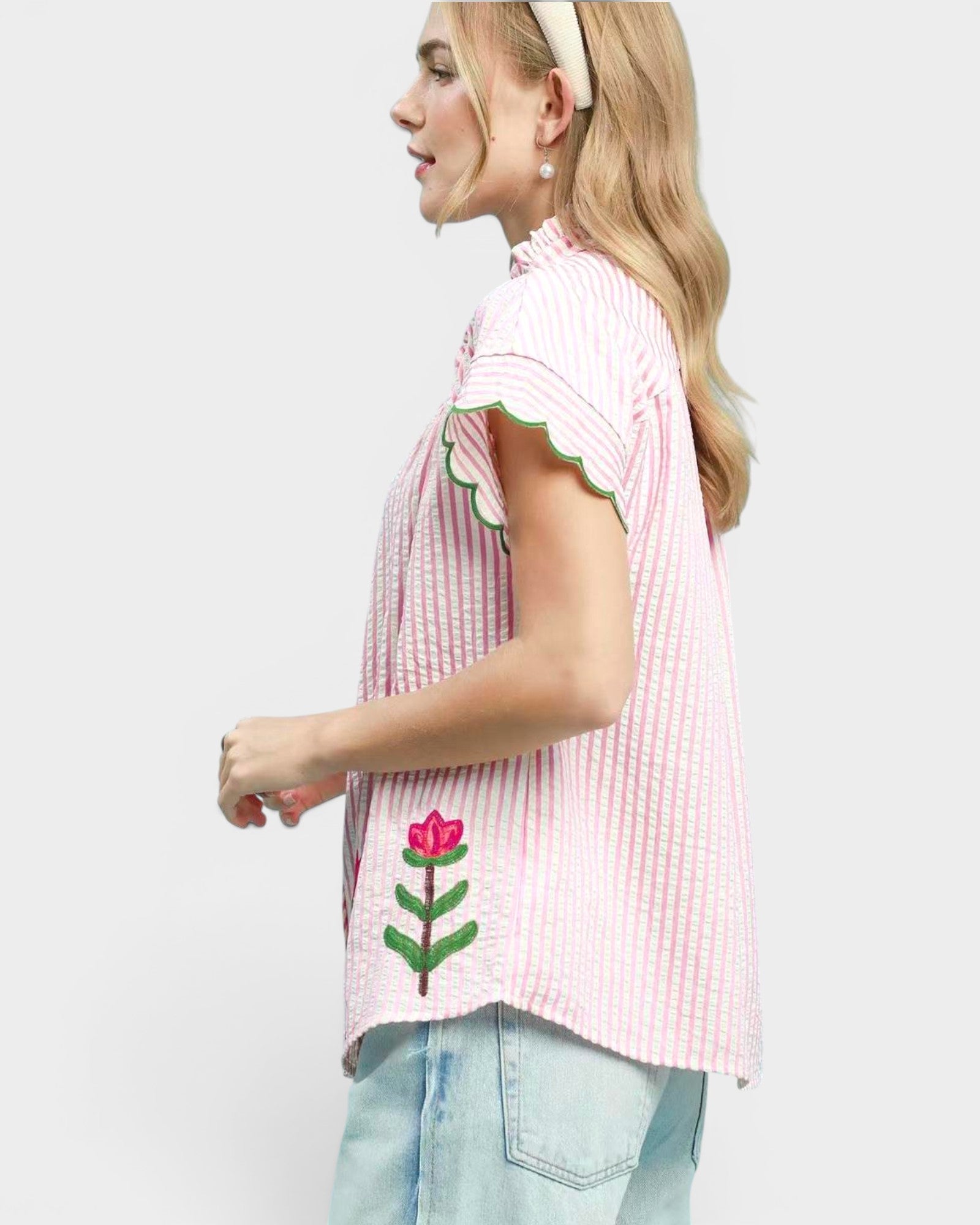Woman wearing a pink checkered shirt with floral designs on a white background
