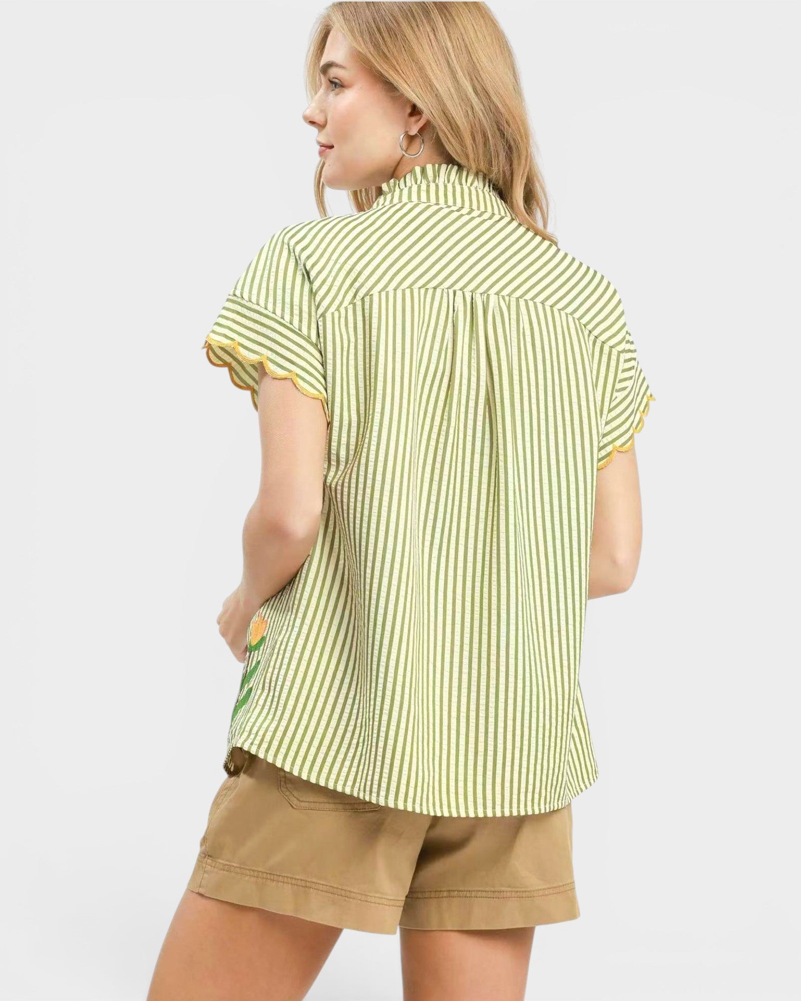 Woman wearing a green and white striped shirt with a small design on a plain background