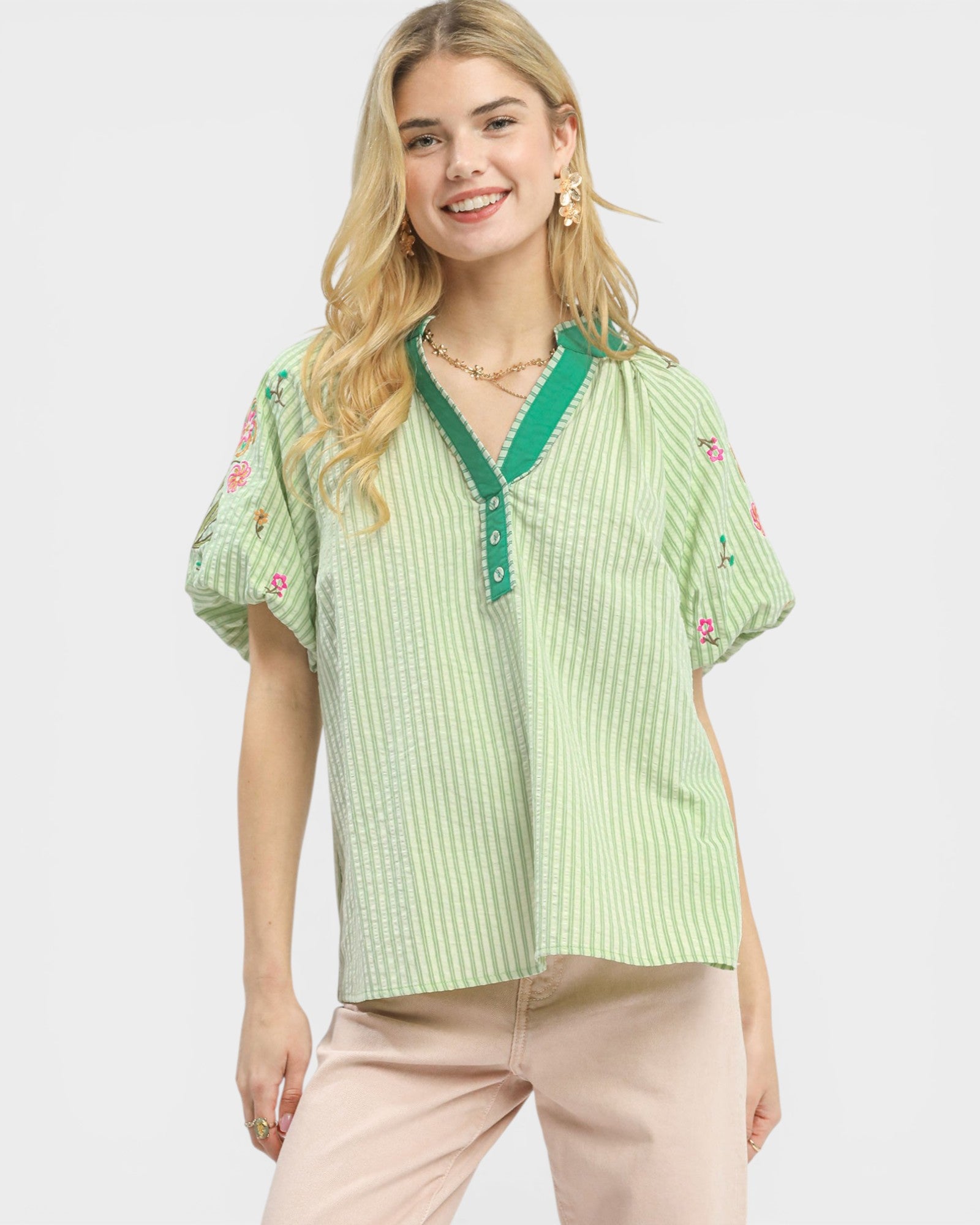 Woman wearing a green embroidered blouse with a plain background
