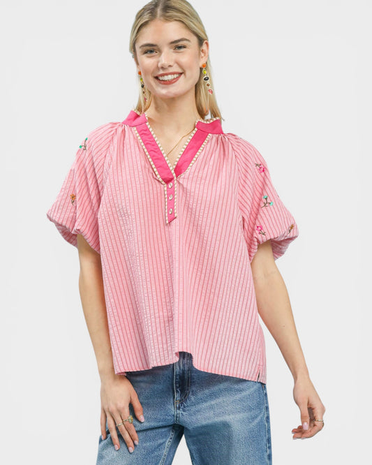 Woman wearing a pink striped shirt with a collar on a white background