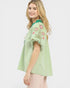 Woman wearing a green striped blouse with floral embroidery on a white background