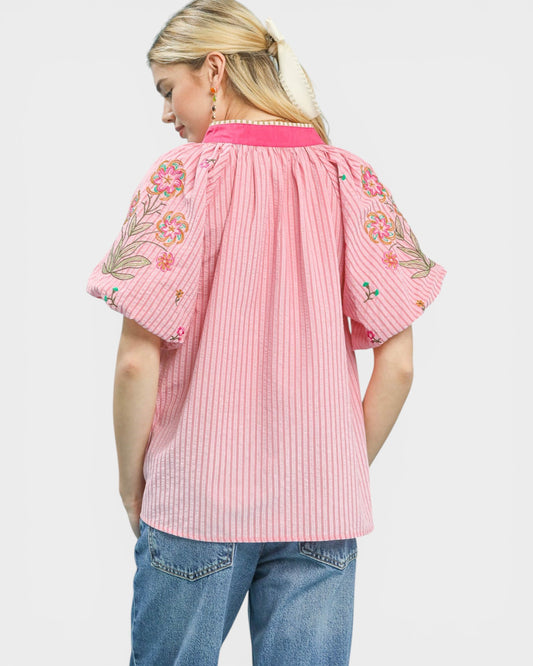 Woman wearing a pink embroidered blouse with a white background