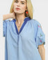 Woman wearing a blue striped shirt with floral embroidery on a white background